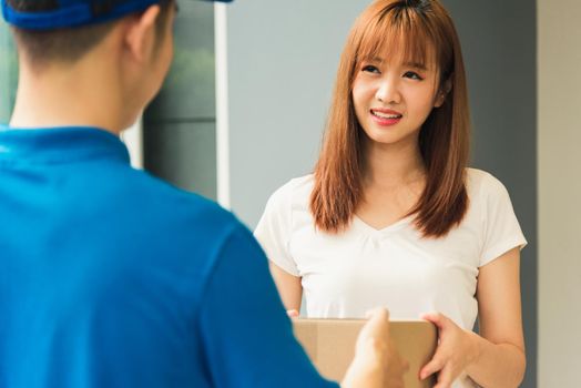 Asian young delivery man courier in uniform hold parcel post boxes service shipment woman customer receiving accepting parcel from delivery at front home, Online shopping service concepts