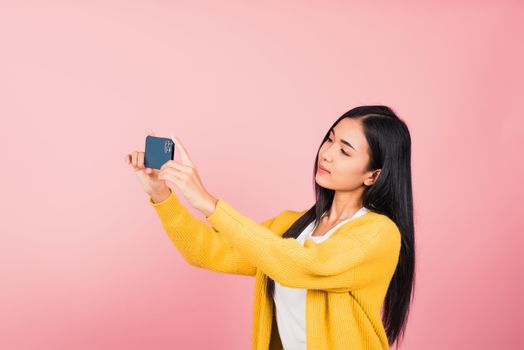 Happy Asian portrait beautiful cute young woman smiling excited  making selfie photo, video call on smartphone studio shot isolated on pink background with copy space