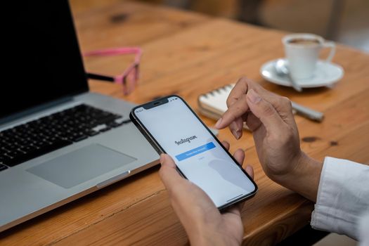 CHIANG MAI, THAILAND - MAY 30 2021: A woman holds Apple iPhone 11 with Instagram application on the screen at cafe. Instagram is a photo-sharing app for smartphones