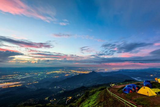 High view beautiful nature landscape of colorful sky during the sunrise, see the lights of the road and city from the campsite at Phu Thap Berk viewpoint, Phetchabun Province, Thailand