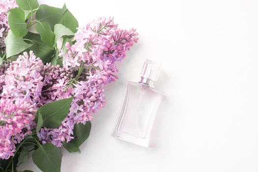 A bottle of perfume and lilac on a white background . Women's perfume. Spring fragrance. Aromatherapy. Nice smell. Beauty and fashion. Article about the choice of fragrance. An article about current flavors . copy space. A branch of lilac. Nature