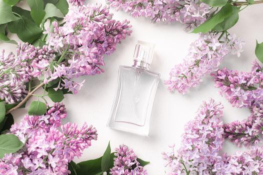 A bottle of perfume and lilac on a white background . Women's perfume. Spring fragrance. Aromatherapy. Nice smell. Beauty and fashion. Article about the choice of fragrance. An article about current flavors . copy space. A branch of lilac. Nature