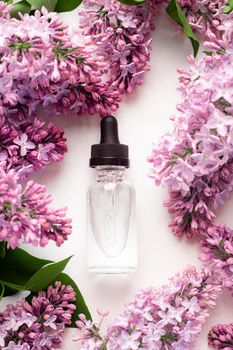 Hyaluronic acid bottle and lilac on a white background . Beauty container. Skin care. Vitamins for the skin. Rejuvenation. Female beauty. An article about the benefits of hyaluronic acid. Article about the choice of hyaluronate. Copy space. A branch of lilac. Flowering . Nature