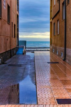 Lonely Little street between buildings facing the sea after a rainy day