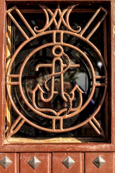 Brown wooden door with anchor detail in wrought iron door in Alicante, Spain