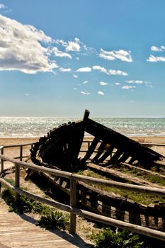 Old abandoned boat on the beach in Santa Pola. Salinas in the background under blue sky