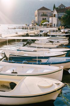 Fishing boats at the pier with houses in the background on a sunny day in Perast, Montenegro. High quality photo