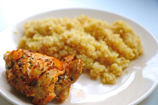 On a plate, a piece of cooked chicken and porridge. Healthy wholesome food