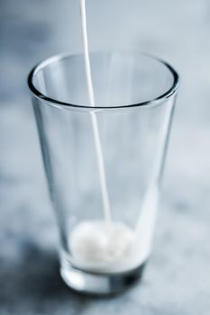 Dairy, healthy nutrition and breakfast concept - World Milk Day, pouring into glass on marble table