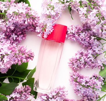 A bottle of perfume and lilac on a white background . Women's perfume. Spring fragrance. Aromatherapy. Nice smell. Beauty and fashion. Article about the choice of fragrance. An article about current flavors . copy space. A branch of lilac. Nature