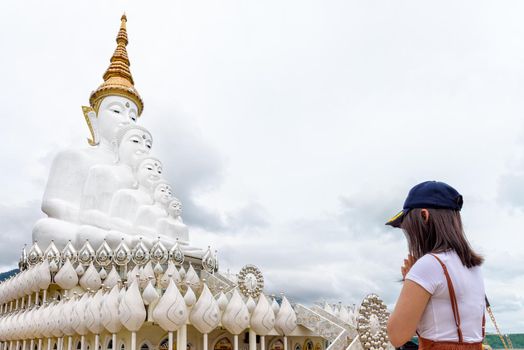 Woman standing worship respect praying for blessing with Buddha statue has large white five body at Wat Phra That Pha Sorn Kaew Temple is a famous tourist attractions in Khao Kho, Phetchabun, Thailand