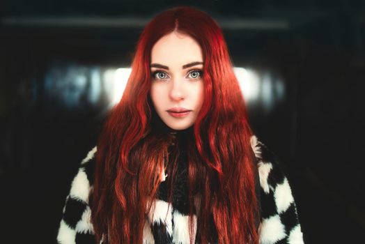 Portrait of a beautiful woman with red hair standing in the underground passage