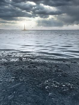 Blue winter ice a winter scene with blue ice with a lighthouse glowing in the distance, against a background of beautiful overcast clouds.