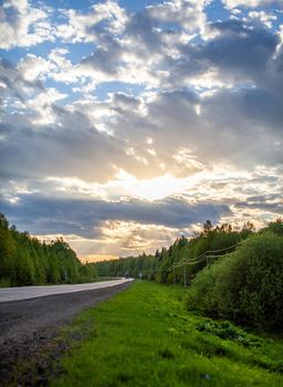 Country road with markings in the middle of the forest. Path and forward movement in the sun. Beautiful, green forest in the spring at sunset. Concept for success in the future goal and passing time