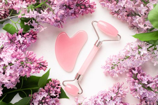 Quartz roller for face and lilac . White background. Skin care. Wellness facial massage. Face lift. Cosmetology. Spa treatments . Copy space