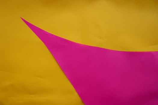 Pink pieces of fabric lie on the yellow fabric.