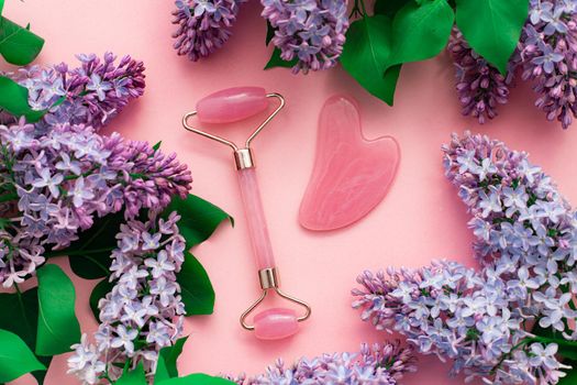 Quartz roller for face and lilac . Pink background. Skin care. Wellness facial massage. Face lift. Cosmetology. Spa treatments . Copy space