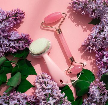 Quartz roller for face and lilac . Pink background. Skin care. Wellness facial massage. Face lift. Cosmetology. Spa treatments . Copy space