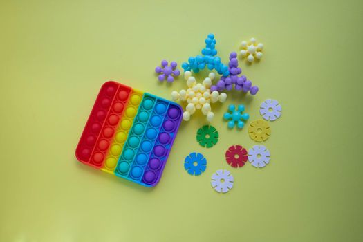 A rainbow toy and puzzles lie on a yellow background. Blue and Orange Funny Interactive Anti-Stress Silicone Toys. Pop it .