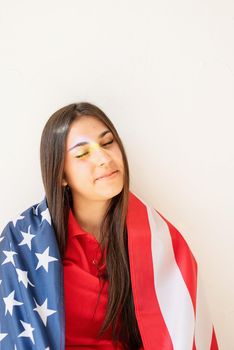 Independence day of the USA. Happy July 4th. beautiful young woman with american flag and rainbow reflection on the face. Copy space