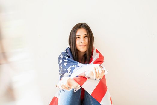 Independence day of the USA. Happy July 4th. beautiful young woman with american flag, prism rainbow reflection on the foreground. Copy space