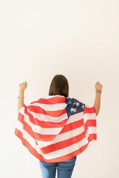 Independence day of the USA. Happy July 4th. young woman with american flag, view from behind. Copy space