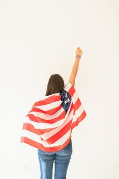 Independence day of the USA. Happy July 4th. young woman with american flag, view from behind. Copy space