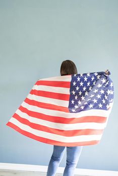 Independence day of the USA. Happy July 4th. beautiful young woman with american flag on blue background, view from behind