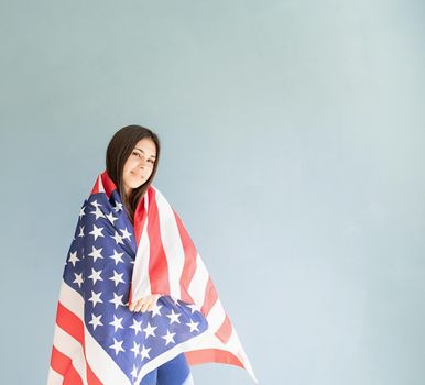 Independence day of the USA. Happy July 4th. beautiful young woman with american flag on blue background. Copy space