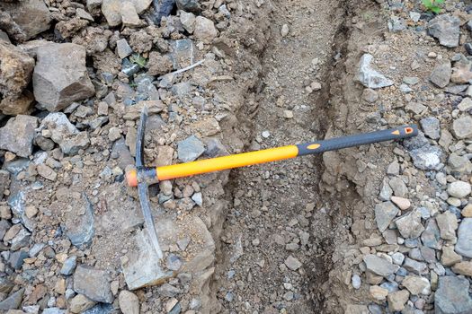 pickaxe hoe lying on the ground. hand-held percussion tool designed for working on stone, stony ground, very dense ground.