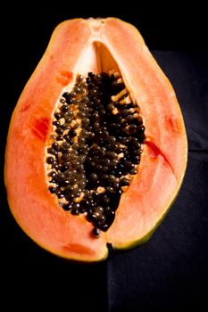 Half of an open papaya with the seeds. No people