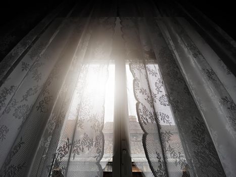 Sunlight coming through a window with lace curtains. Home interior.