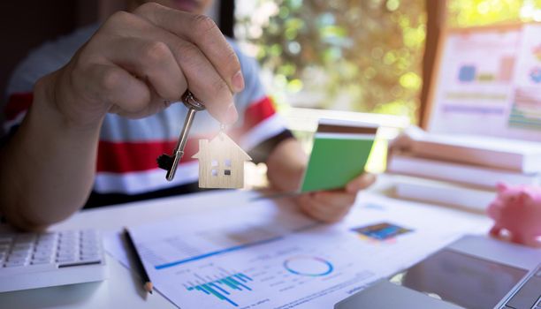 Young male or Professional entrepreneur showing key house and holding saving money passbook. Concept of saving and planning to buy housing property.