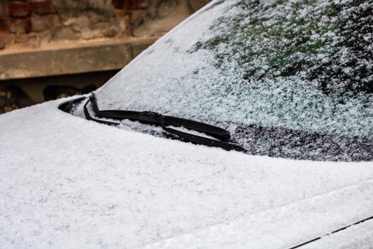 Snow on car, windshield wipers with snow close up.