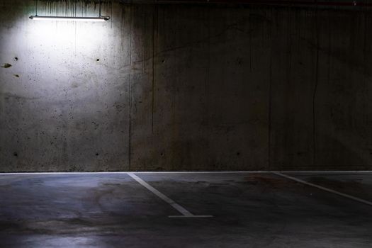 Empty parking lot with overhead dim light, underground parking garage.