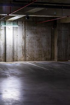 Empty parking lot with overhead dim light, underground parking garage.