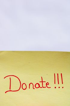 Donate handwriting text close up isolated on yellow paper with copy space.