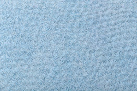 Light blue fluffy fabric background. Top view of bright blue fiber. Abstract textured background with space for text