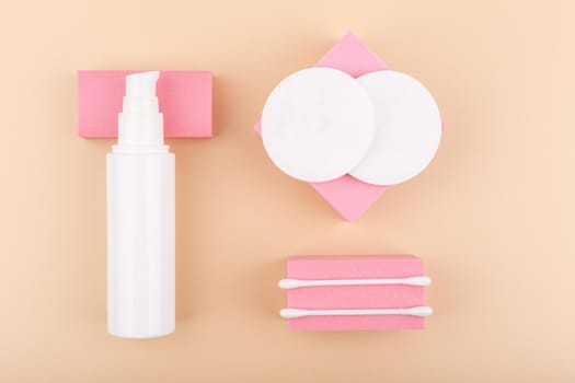 Creative flat lay with make up removing product, cotton pads and cotton swabs on pink podiums against beige background. Concept of skin care and make up removing