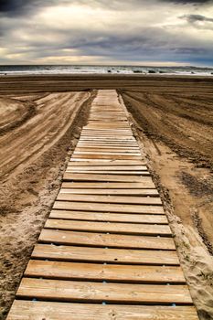 Wooden walkway to the beach in the morning in a cloudy day