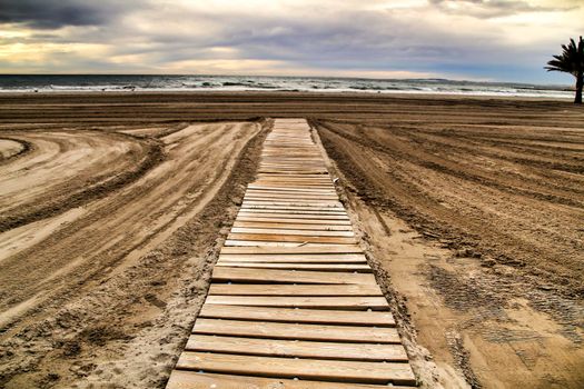 Wooden walkway to the beach in the morning in a cloudy day