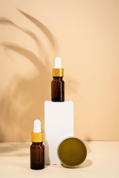 Natural organic selfcare products. Brown bottles mockup for natural skincare essential oils, spa accessories on white podiums, cream background. Spa accessories creative art composition on beige background