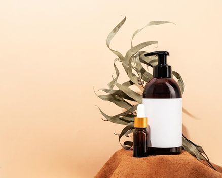 Natural organic selfcare products. Brown bottles mockup for natural cosmetics, spa accessories on brown leather podium, cream background and leaves. Spa accessories creative art composition on beige background