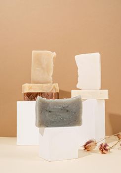 Natural organic selfcare products. Tower stack of different handmade soaps and leaves on cream background. Spa accessories creative art composition on beige background