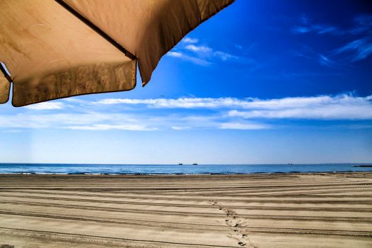 Sunny day on the beach in winter in Santa Pola, Alicante. White Umbrella in the foreground.