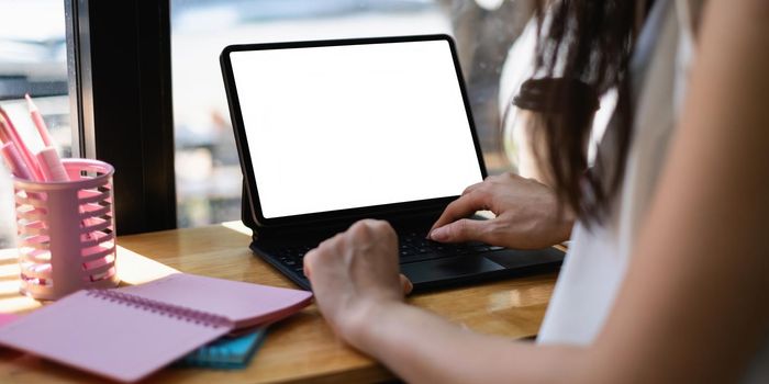 Mockup image of a black tablet with white blank screen on wooden desk