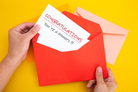 Hand open a red envelope with letter Congratulations You're a winner!