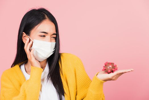 Portrait of Asian young woman wear face mask protective holding DNA strand of Coronavirus (COVID-19, 2019-ncov) genetic instruction, new strain RNA mutation, studio shot isolated on pink background