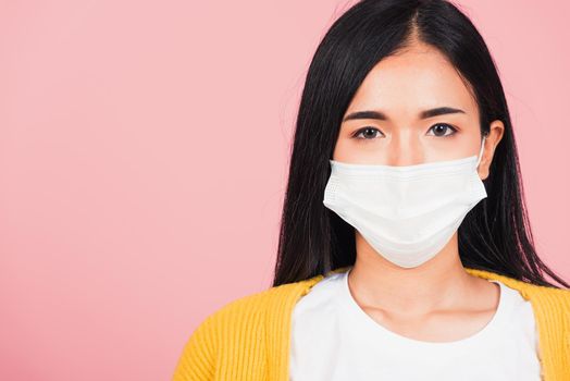 Closeup face Asian beautiful young woman wearing medical mask protection against germs for prevent infection coronavirus, COVID-19, studio shot isolated on pink background, medical health care concept