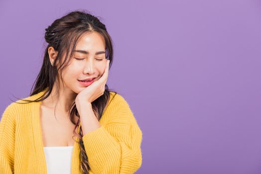 Portrait of Asian beautiful young woman suffering from toothache, female terrible strong teeth pain problem pressing hand to chin, studio shot isolated on purple background, Dental health care concept